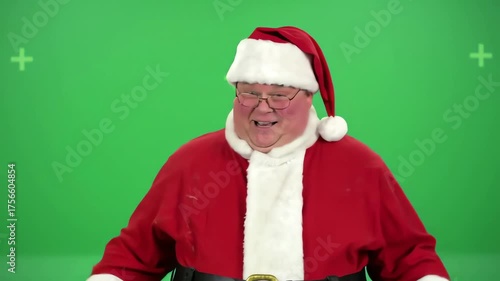 A man in a Santa suit stands against a green screen