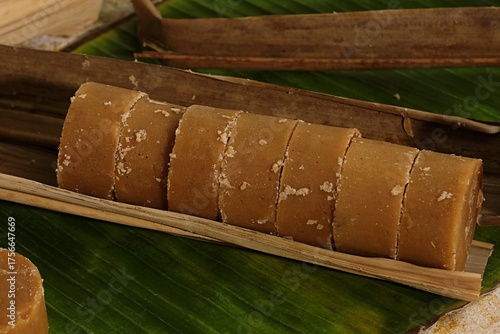 Schilderij op canvas Rolled palm sugar or gula aren placed on banana leaf, traditional Indonesian sweetener, rustic and organic food concept