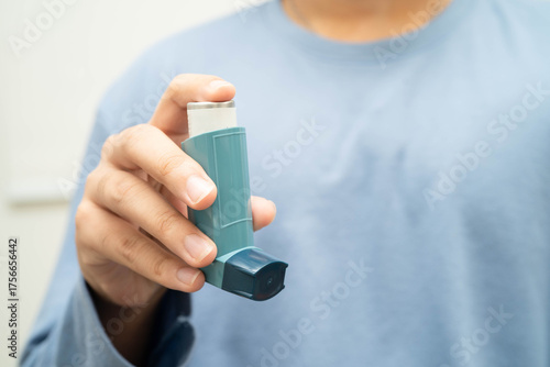 Asthma and chronic obstructive pulmonary disease COPD, Asian young man using metered dose inhaler MDI.