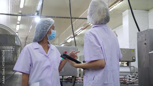 Inspector team working quality control in food processing factory, two worker woman in uniform and mask using tablet for monitoring hygiene and production for examining quality and supply chain.