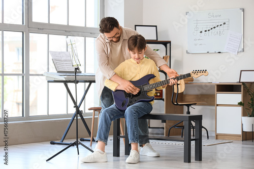 Private music teacher giving guitar lessons to boy in room
