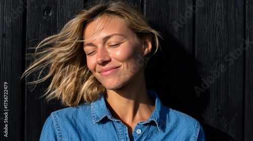 Woman posing outdoors with sunglasses and blue shirt.