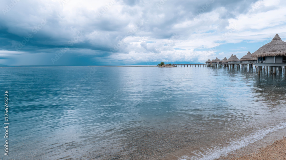 Fototapeta premium Tranquil Turquoise Ocean Scene with Gentle Rolling Waves Under a Cloudy Sky and Overwater Bungalows on the Horizon