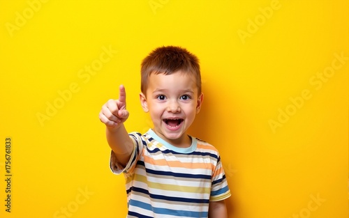 idea. child, boy emotionally points up. A gesture of an idea. Portrait of a child in a bright striped T-shirt on a yellow background. High quality
