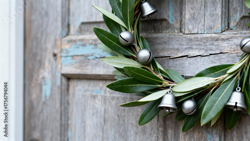 Hyperrealistic detail of a minimalist wreath made of fresh laurel branches and silver bells on a wooden door