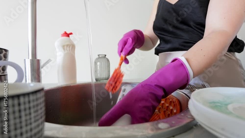 Washing sticky container thoroughly now, Person diligently rinses jar with flowing water, Person carefully washing sticky red sauce jar under running water before drying