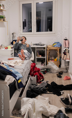 Teenage girl relaxing in messy untidy bedroom