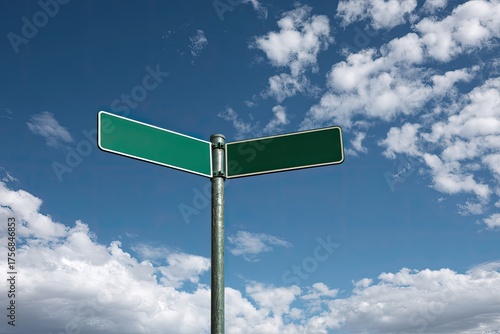 Blank, green street signs pointing in opposite directions against a partly cloudy, blue sky
