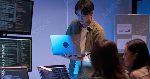 Fényképezés Group of young Asian developers collaborating during nighttime coding session