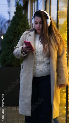 young woman standing outdoors on night neon street cafe illuminated for new year, drinking coffee to go