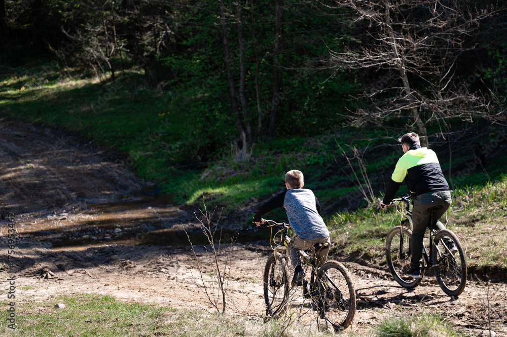 Naklejka premium Father and son enjoy a bike ride on a trail through the woods.