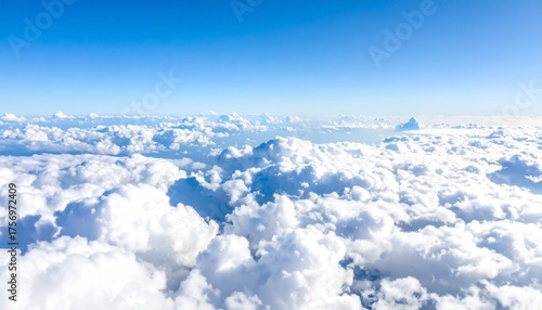 Soaring above a vast sea of fluffy white clouds under a brilliant clear blue sky, offering a serene and expansive aerial vista