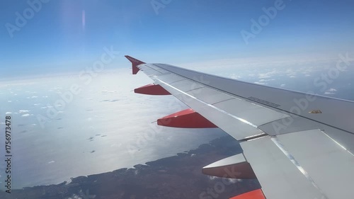 Airplane wing flying over coastline and sea
