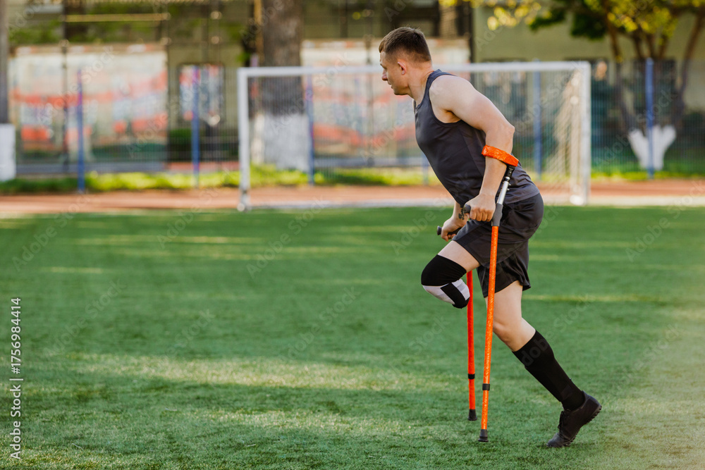 Fototapeta premium A man leans on crutches while running across a field