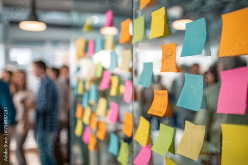 Brainstorming session with sticky notes on glass wall, focus on colorful notes. Tasks for the day. Marketing department office setup.