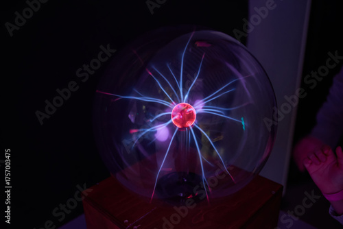 A person touching a plasma ball in a dark room.