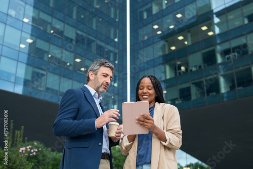 Diverse business colleagues discussing while watching tablet outdoors