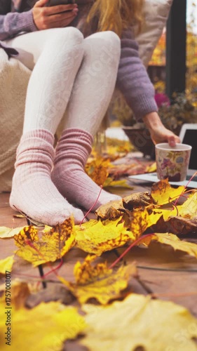 Cozy autumn morning on a wooden terrace with warm socks, blanket, and coffee. Peaceful fall mood, golden leaves, soft light, sweater weather lifestyle and comfort in nature.
