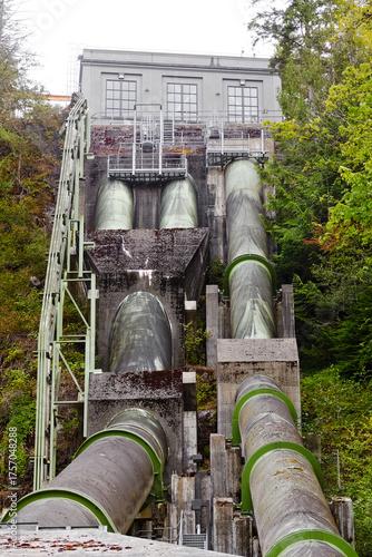 Massive pipes descend a hillside leading to the Snoqualmie Falls hydroelectric power plant, showcasing renewable energy and industrial engineering design.
