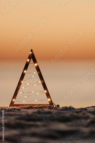 Boho driftwood Christmas tree illuminated with micro fairy lights on a beach in Australia.  Muted hues