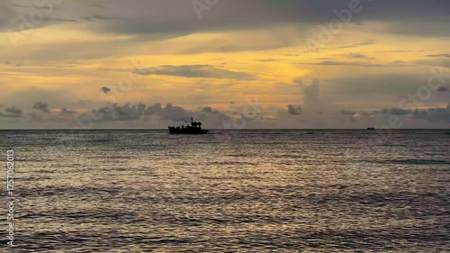 Fishing boats are sailing in the middle of the sea at sunset.