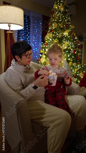 Grandmother tells Christmas stories to her grandson by the fireplace. Warm light, festive tree, and cozy winter night create a magical family moment full of love, peace, and holiday spirit.