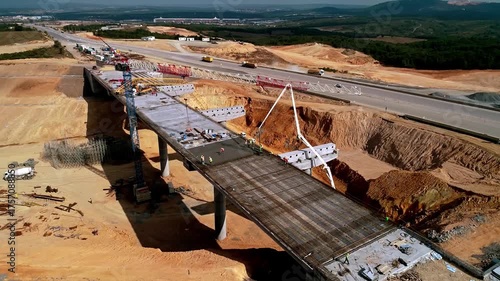 Drone footage of bridge and highway construction site with concrete work, steel structures, and heavy equipment. Large-scale infrastructure and civil engineering project.