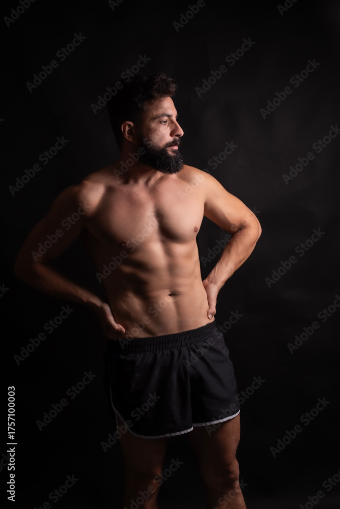 Fototapeta premium Middle-aged man with beard and Arab Hispanic features posing fit body in studio portrait