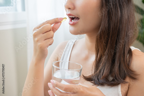 Dietary supplement, asian young woman, girl hand holding fish oil pills, drugs medical, take or eat vitamin for treatment skin, hair and nail strengthen with glass of water at home. Healthcare concept