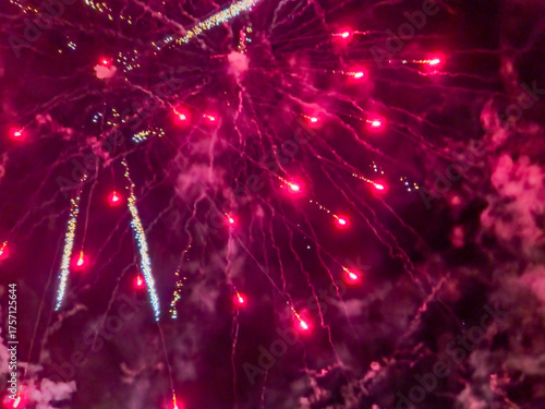 Fireworks light up the night sky. Bright bursts and glowing trails create an impressive display with a dark background.