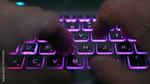 Macro view of hands typing on illuminated laptop keyboard with RGB backlight. Concept of technology, digital work, programming, communication, and modern lifestyle