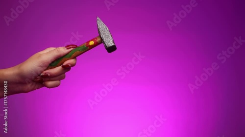 A young woman is using a decorated hammer and hitting hard with it. Representing women's strength, women's rights, and women in the workforce. Feminism. Woman empowerment