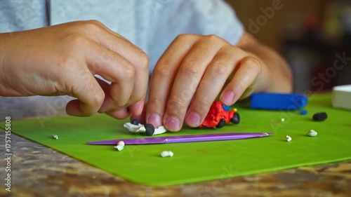 Front view of a 9-year-old boy at the table shaping toy cars from colorful modeling clay, closeup with focus on hands and creative process.