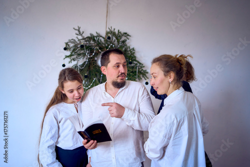 a family with toddler and teenager reading the Bible during Christmas celebration