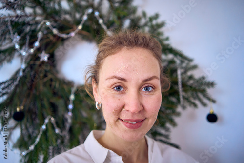 portrait of a young woman with a face covered in gold glitter during a Christmas party at home