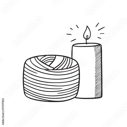 A spool of yarn beside a candle glowing softly
