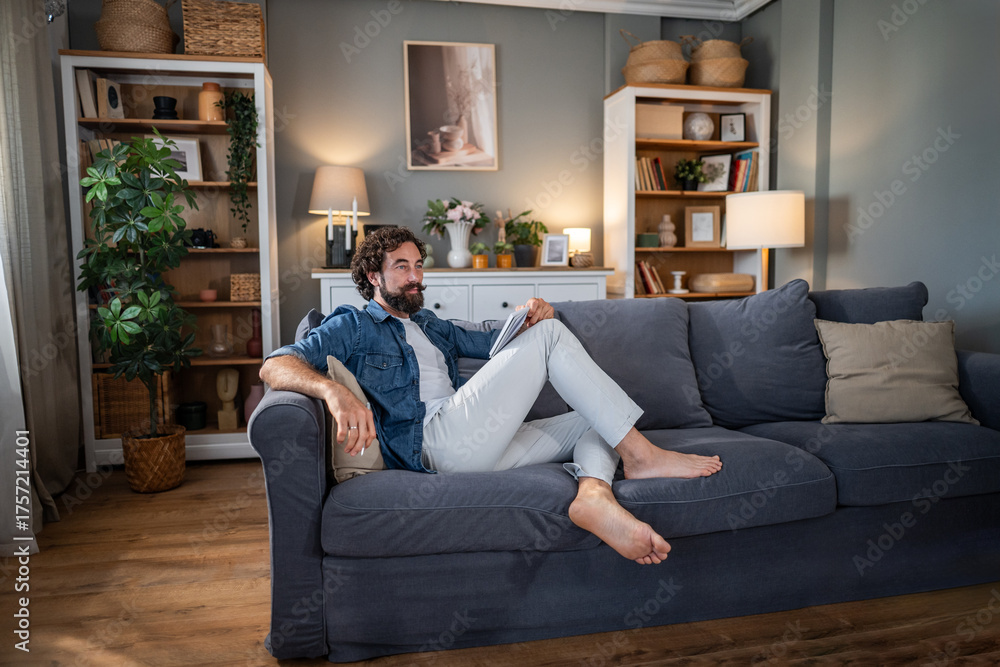 Obraz premium Man relaxing on cozy couch watching tablet