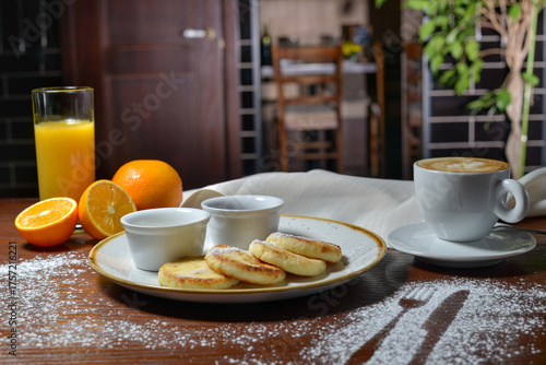 breakfast cheesecakes with sauces in a plate on a table with coffee and oranges