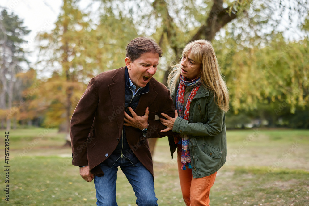 Fototapeta premium Man experiencing heart attack in park, woman helping
