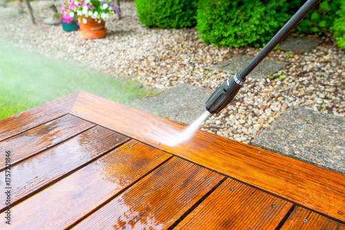 cleaning terrace with a power washer - high water pressure cleaner on wooden terrace surface