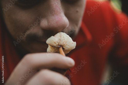 Homme sentant un champignon en gros plan — interaction avec la nature, découverte et exploration forestière, détail de la main et du champignon