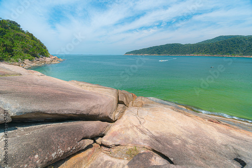 Guaiuba Beach, Guaruja SP, Brazil. Sunny day over the small bay with tranquil sea. Image of leisure and tourism on the Sao Paulo coast. Hills covered in Mata Atlantica vegetation frame the view.