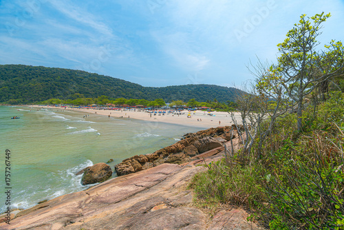 Guaiuba Beach, Guaruja SP, Brazil. Sunny day over the small bay with tranquil sea. Image of leisure and tourism on the Sao Paulo coast. Hills covered in Mata Atlantica vegetation frame the view.