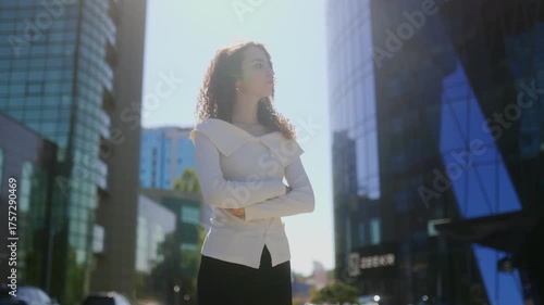 Young curly-haired woman waiting confidently outdoors in urban setting