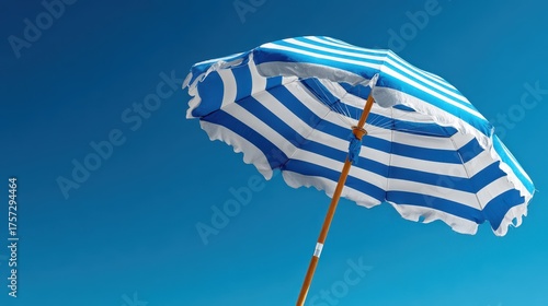 Striped Blue And White Beach Umbrella Set Against Clear Sky On Sunny