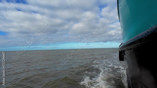 A small boat elegantly glides through the calm, serene waters beneath a stunning, dramatic, and beautiful cloudy sky