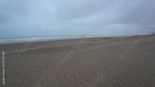 A tranquil beach with gentle waves lapping the shore under a cloudy sky, perfect for relaxation and peace