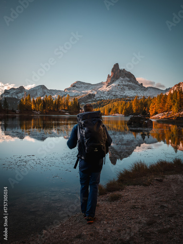 Hiker is standing at mountain lake federa in the dolomites at sunrise in autumn