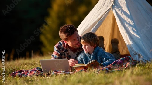 Father son camping reading laptop tent outdoors