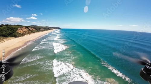 Aerial view of ocean waves crashing on sandy beach during sunny day